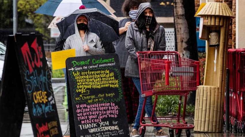 RIVERSIDE, CA- APRIL 9, 2020: Despite the rain and chilly weather, customers are still lining up outside Trader Joe’s to shop during the coronavirus pandemic on April 9, 2020 in Riverside, California.(Gina Ferazzi / Los Angeles Times via Getty Images)