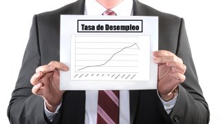 Hombre sostiene hoja con gráfico que muestra tendencia de la tasa de desempleo.