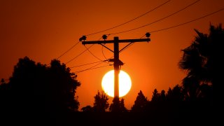 In this Sept. 3, 2020, file photo, the sun sets behind power lines in Los Angeles, California, ahead of a heatwave.
