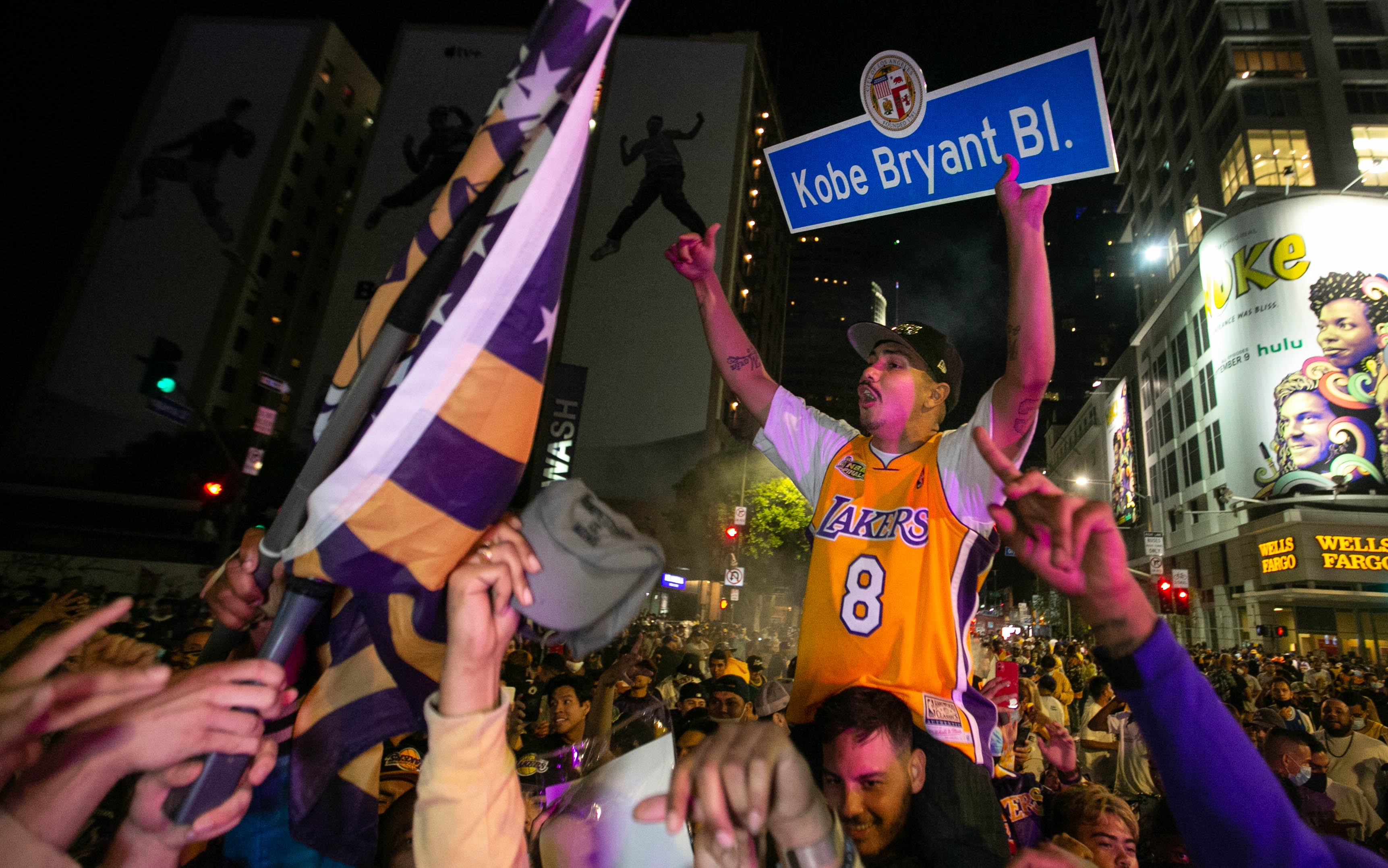 LOS ÁNGELES, CA - 11 de octubre: un hombre sostiene aviso del Bulevar Kobe Bryant mientras  otros fanáticos celebran la victoria del campeonato de los Lakers 106-93 contra el Miami Heat el domingo 11 de octubre de 2020 en Los Ángeles, California. (Jason Armond / Los Angeles Times a través de Getty Images)