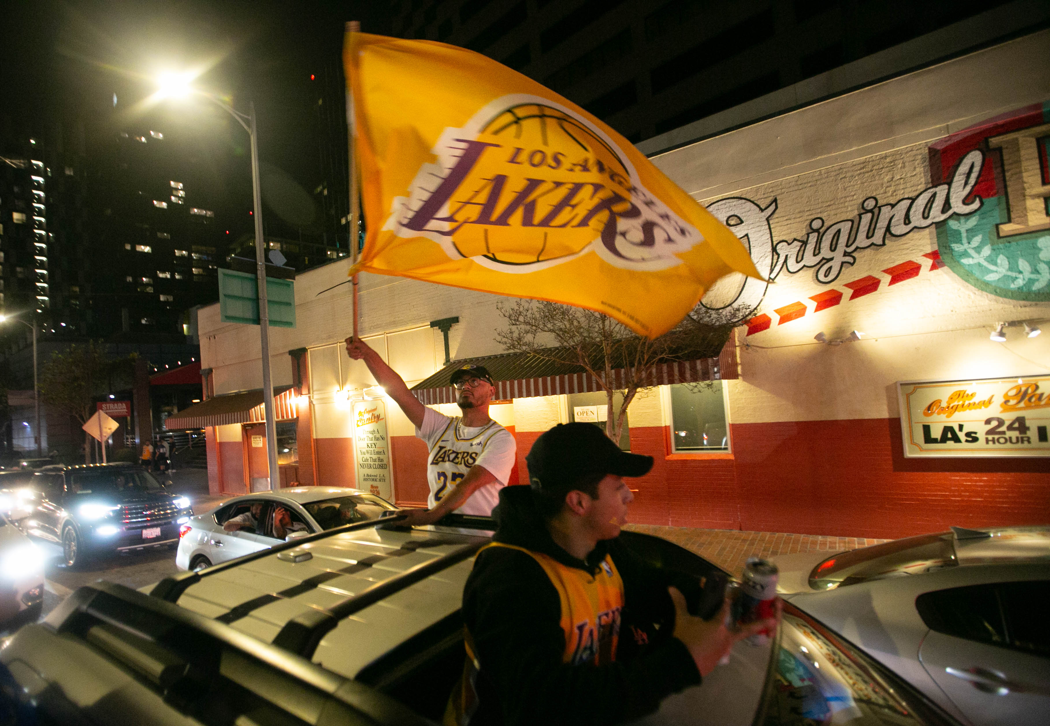 LOS ÁNGELES, CA - 11 DE OCTUBRE: Un fanático de los Lakers de Los Ángeles sostiene una bandera mientras se cuelga fuera de la ventana en celebración del campeonato de los Lakers 106-93 contra el Miami Heat el domingo 11 de octubre de 2020 en Los Ángeles, California. (Jason Armond / Los Angeles Times a través de Getty Images)