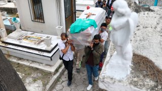 Personas cargan un ataúd en un cementerio mexicano