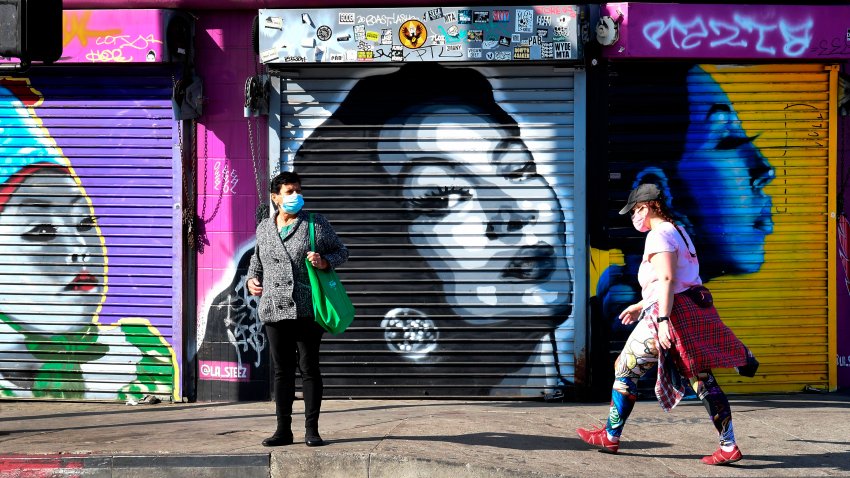 mujeres con cubrebocas frente a tiendas cerradas en Los Angeles por coronavirus y mural de María Felix