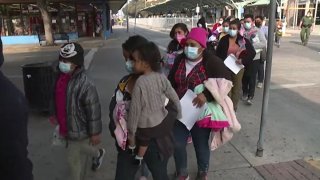 Foto de migrantes haciendo fila en la central de autobuses de McAllen.