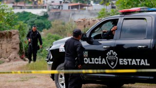 Un par de policías vigilan un paraje en el que hallaron muertos a tres hermanos