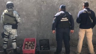 Fotografía de tres agentes junto a una caja de explosivos artesanales