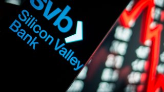 Ilustración fotográfica, el logotipo de Silicon Valley Bank es visible en un teléfono inteligente, con el índice bursátil en el fondo de la computadora personal el 14 de marzo de 2023, en Roma, Italia.