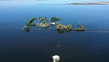 An aerial view of a home (C) surrounded by floodwaters in the reemerging Tulare Lake, in California’s Central Valley, on April 14, 2023 in Corcoran, California.