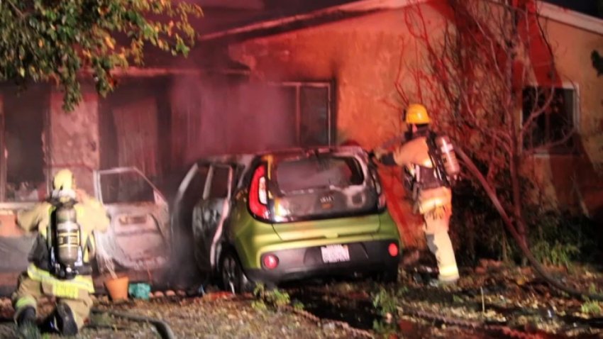 A green Kia crashes into the front of a home.