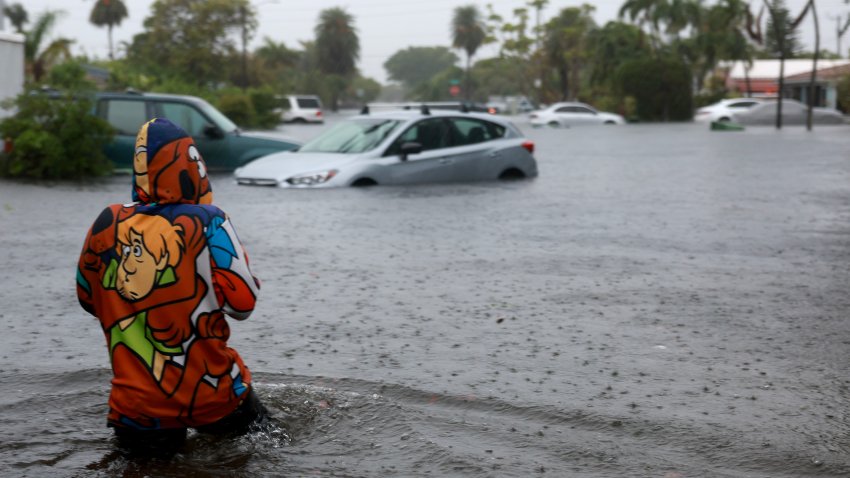 HOLLYWOOD, FLORIDA – JUNE 12: A person walks through a flooded street on June 12, 2024, in Hollywood, Florida. As tropical moisture passes through the area, areas have become flooded due to the heavy rain.  (Photo by Joe Raedle/Getty Images)