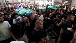 Dolientes marchan durante un funeral con los cadáveres de los palestinos.