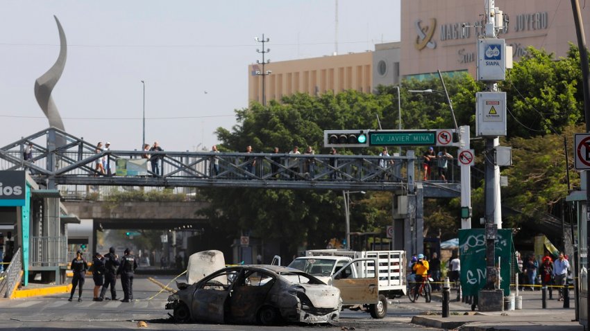 Fotografía que muestra un bloqueo con vehículos incendiados este domingo, en una vía de Guadalajara (México). EFE/ Francisco Guasco